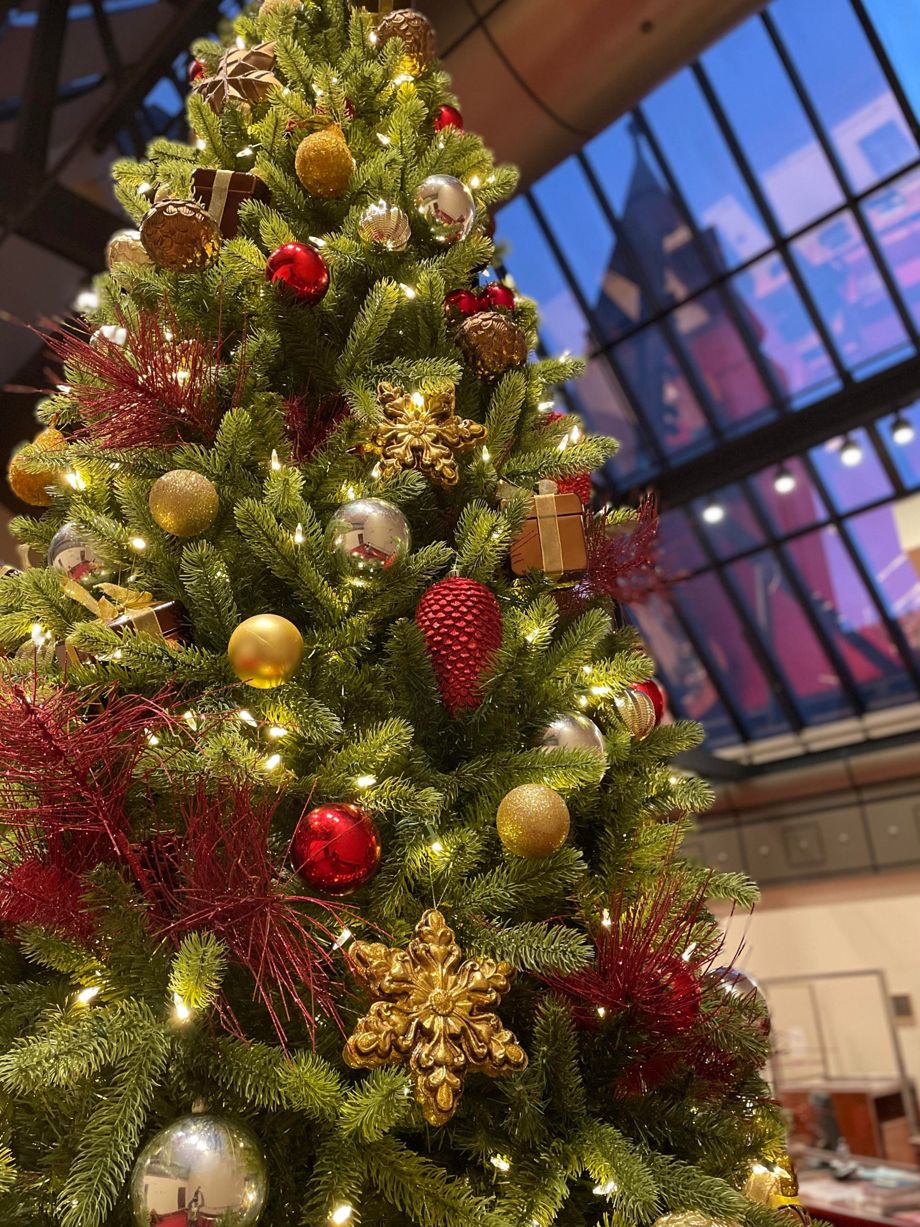Close-up of a lit Christmas tree with red and gold baubles, gold snowflakes and red pinecones