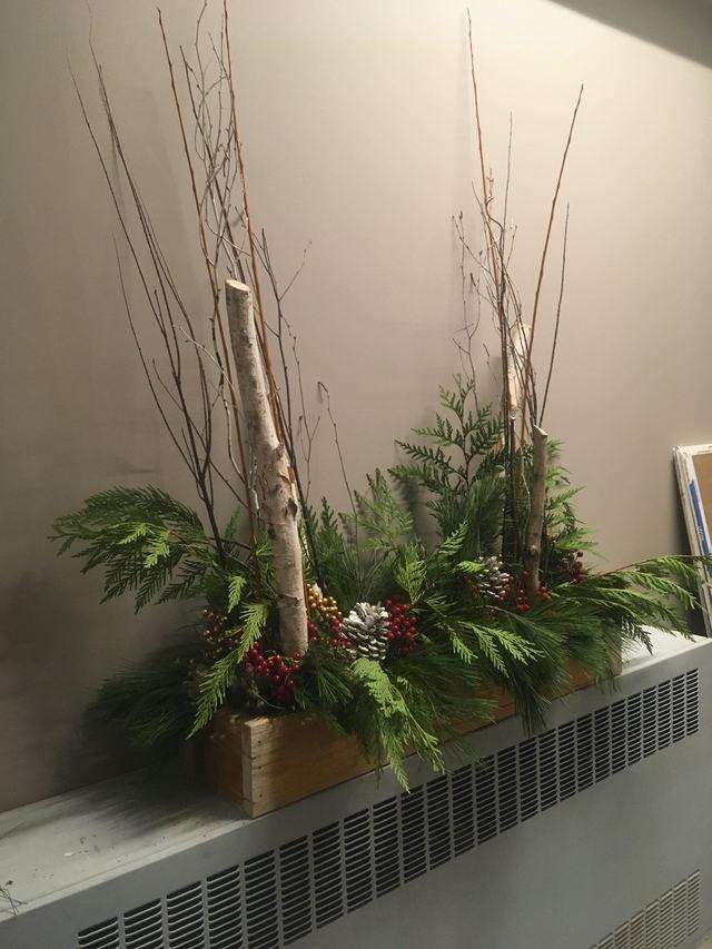 Birch branches and fresh greenery arranged in a wooden planter box