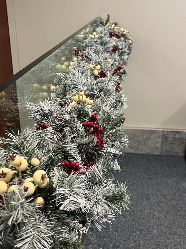Close-up of flocked garland with red berries and gold fruit on a glass balustrade