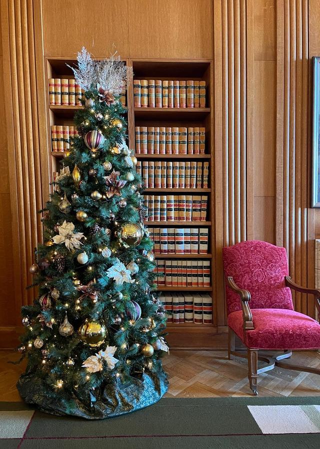 Teal Christmas tree with gold baubles in a wood-panelled library