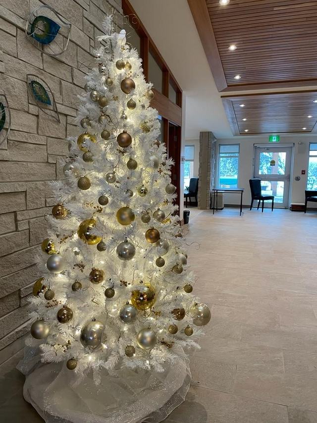 White Christmas tree with gold and champagne baubles in a stone-walled lobby