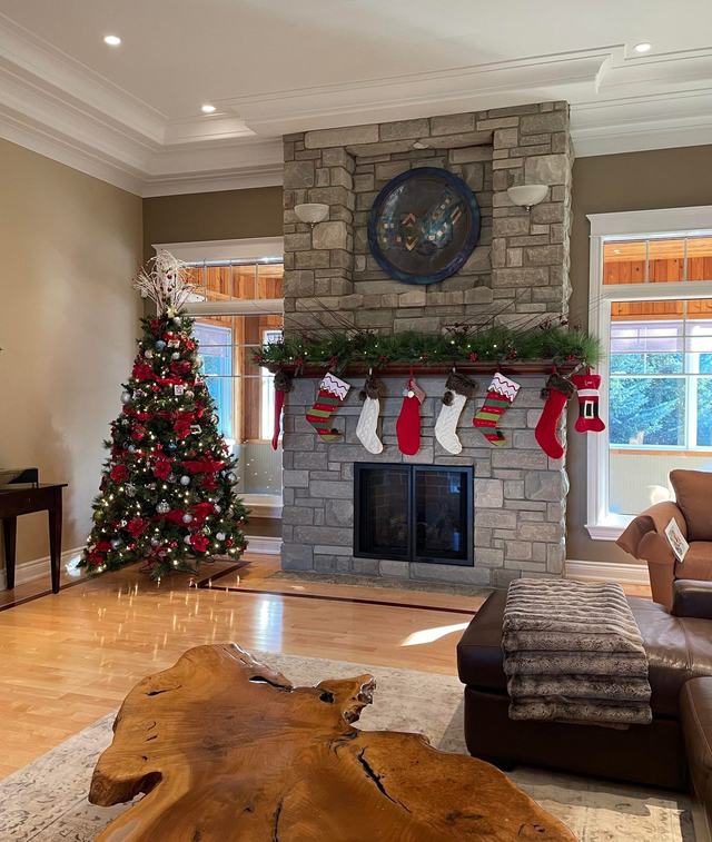 Red and white Christmas tree beside a stone fireplace hung with stockings