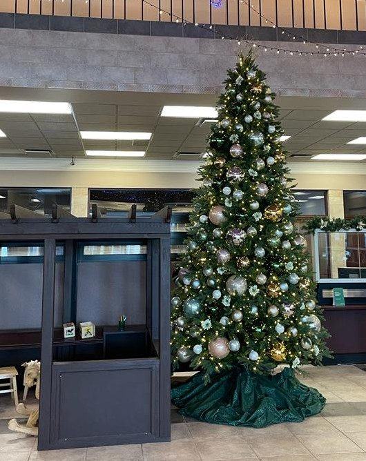 Christmas tree with icy blue and silver baubles and a green tree skirt in a banking hall