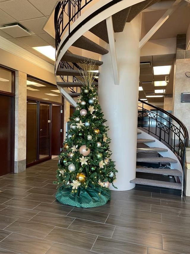 Slim Christmas tree with gold and cream decorations beside a spiral staircase