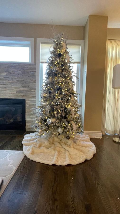 Slim flocked Christmas tree with a cream faux fur skirt in a lounge