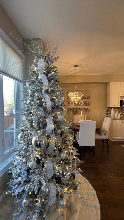 Flocked Christmas tree with silver and white ribbon in a dining room