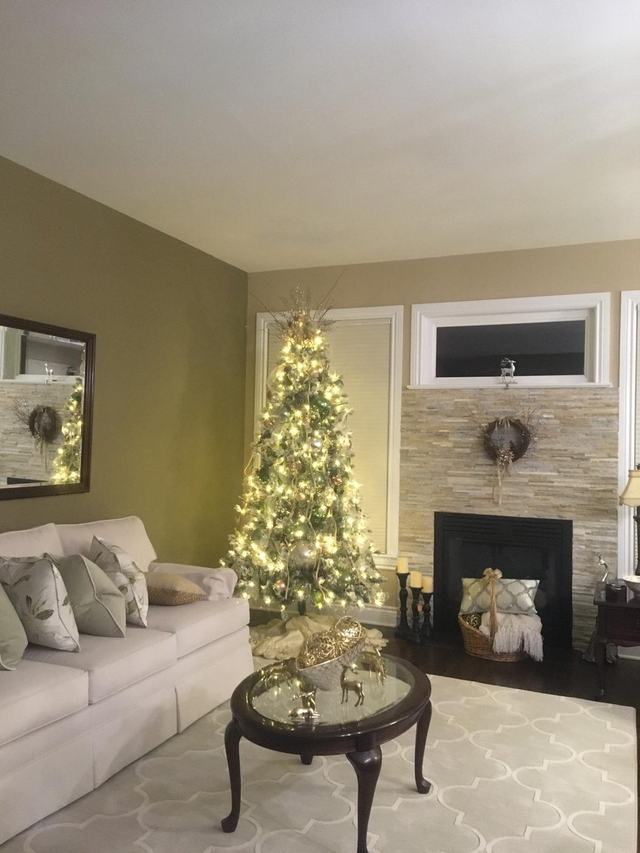 Warmly lit Christmas tree in a cosy lounge with a stone fireplace
