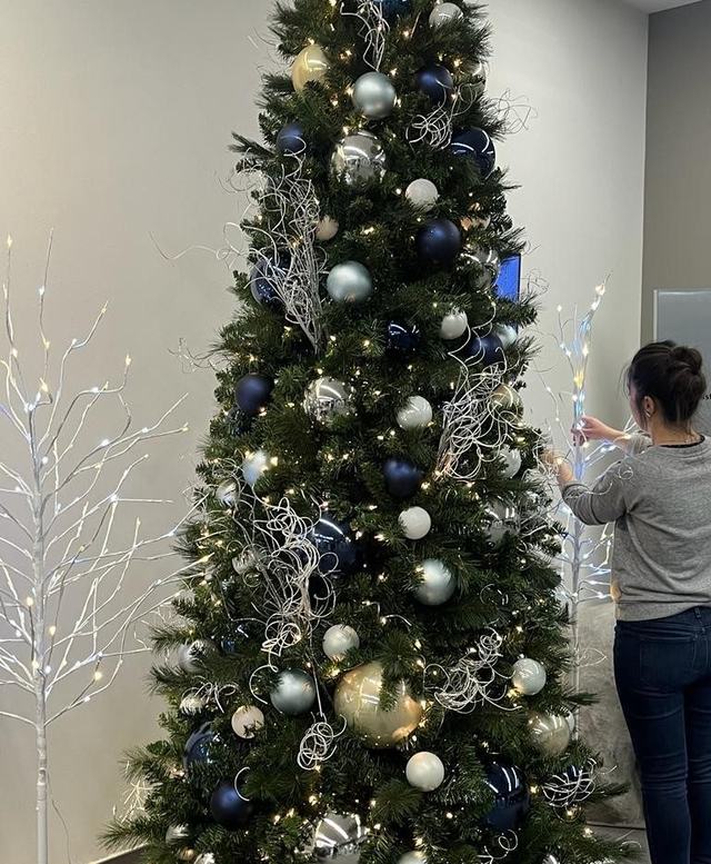 Decorator adding navy and silver baubles to a Christmas tree